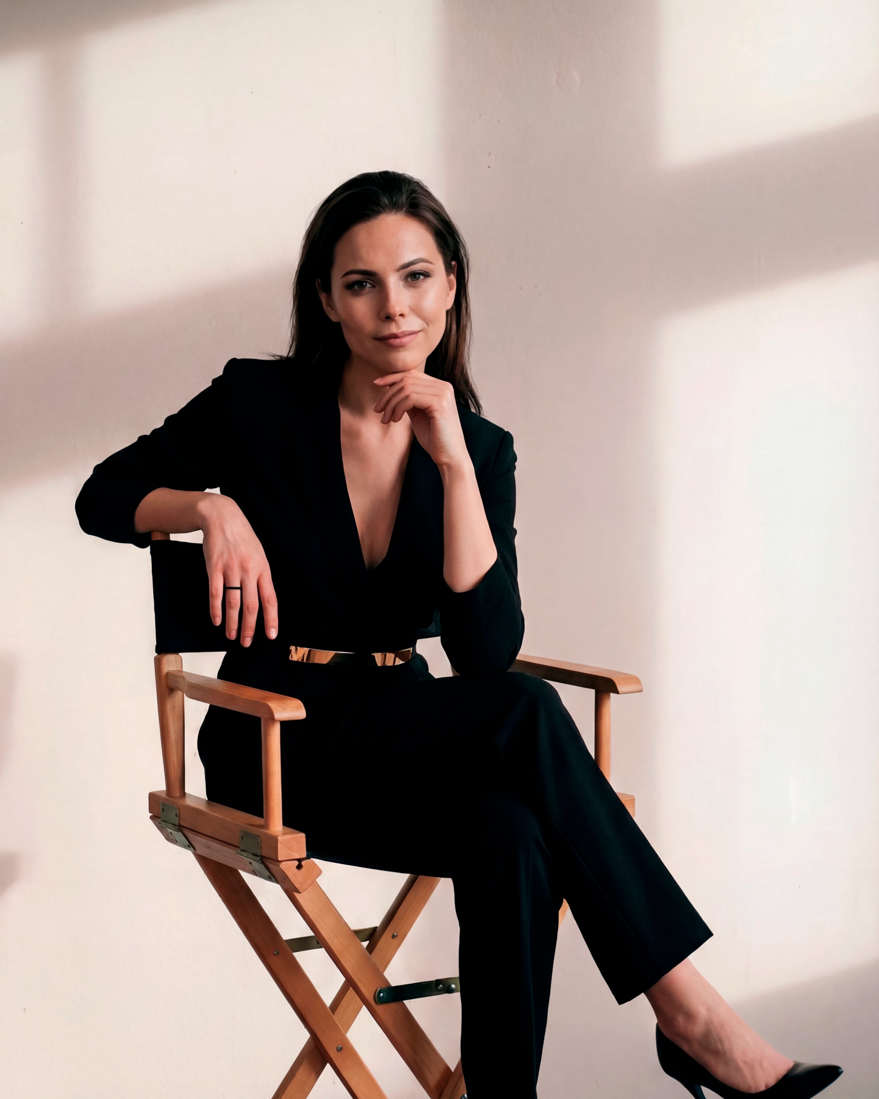 Confident woman seated in a minimalist studio, wearing a tailored black suit and a Dimis Designs Gratitude Ring in black zirconium, embodying modern elegance and intentional luxury.